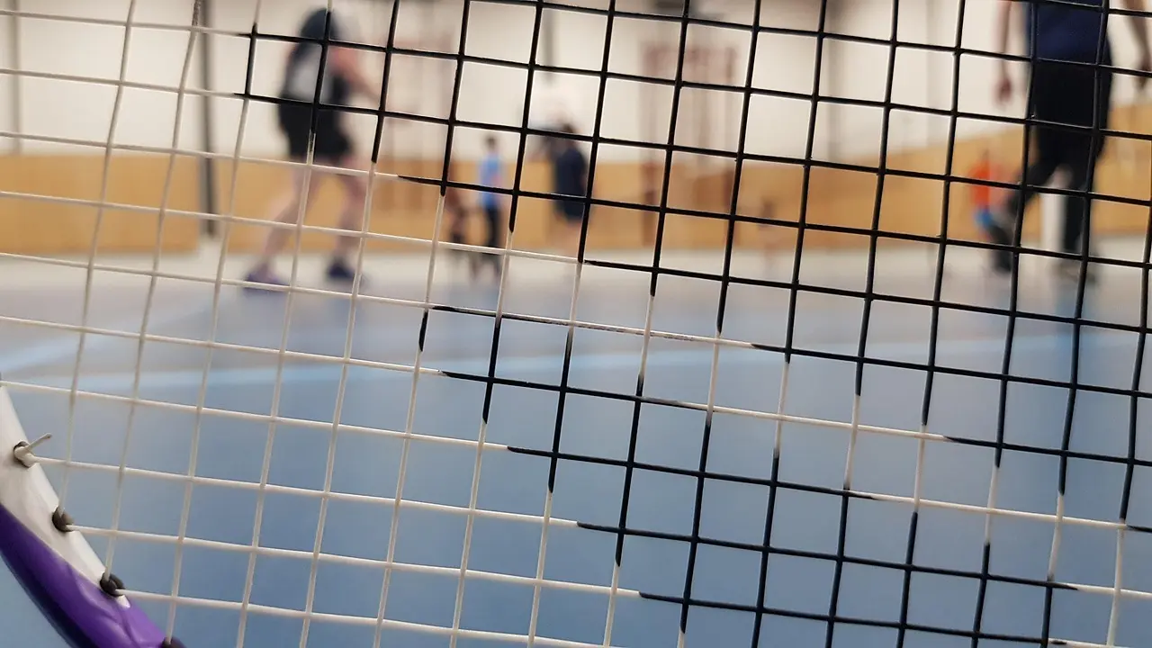 Badmintonketcher foran en indendørs badmintonbane